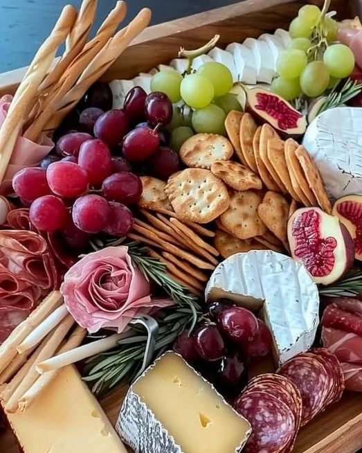 Mesa de quesos decorada para una reunión con varios tipos de quesos y acompañamientos.