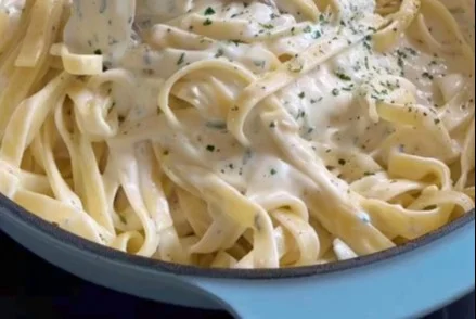Plato de Fettuccine Alfredo servido con queso parmesano y perejil fresco.