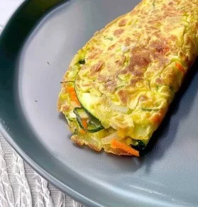 Tortilla de calabacín y zanahoria presentada en un plato blanco