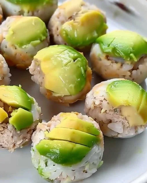 Bolitas de sushi decoradas con ingredientes frescos y coloridos en un plato