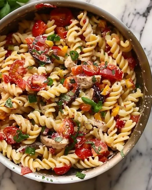 Ensalada de pasta de verano fresca y colorida con verduras y aderezo.