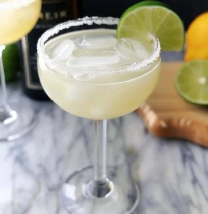 Cóctel margarita clásica con limón y sal en el borde del vaso.