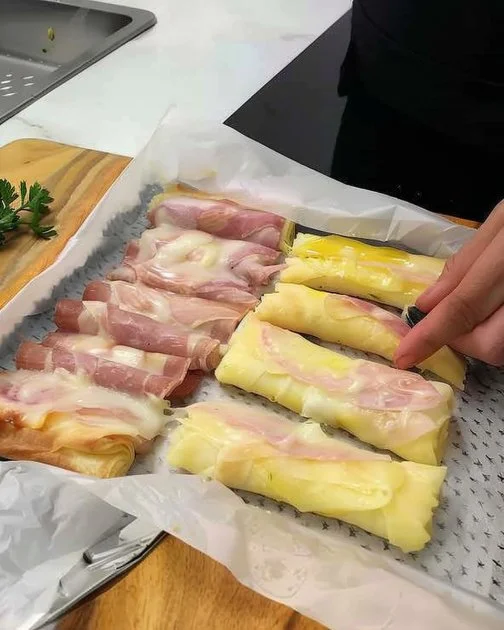 Mini napolitanas de hojaldre rellenas de jamón y queso recién horneadas.