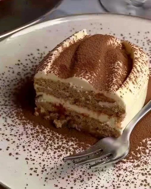 Tiramisú clásico italiano decorado con cacao y café en un plato.