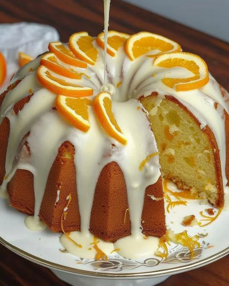 Bizcocho de Naranja con cobertura de glaseado y rodajas de naranja fresca.