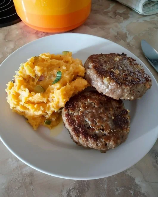 Puré mezclado servido junto a hamburguesas en un plato colorido.