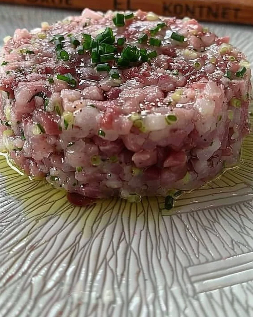 Plato de tartar de fuet presentado con ingredientes frescos y coloridos