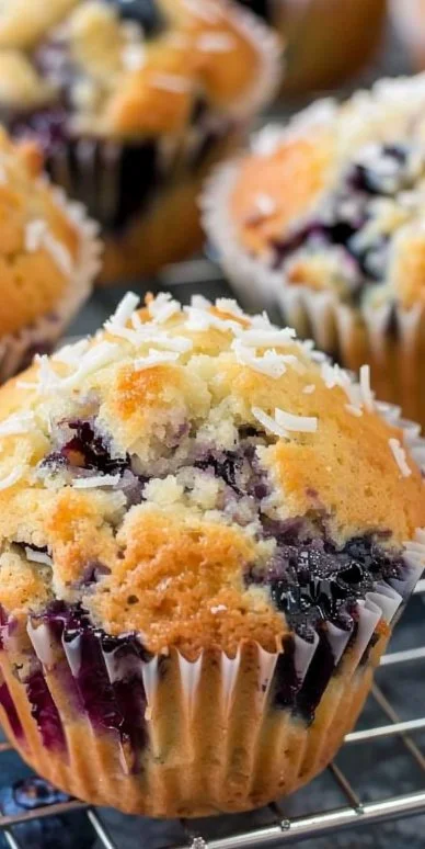 Muffins de arándanos y coco recién horneados sobre una mesa.