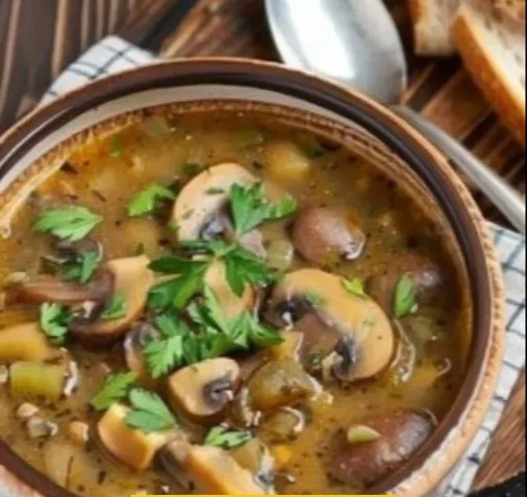 Plato de sopa de champiñones en un tazón, garnished con perejil fresco.