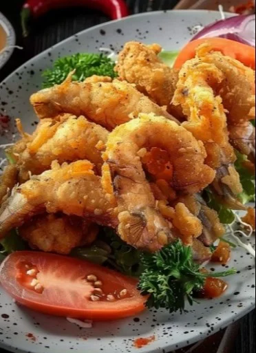 Plato de chicharrón de pescado crujiente acompañado de limón y salsa.